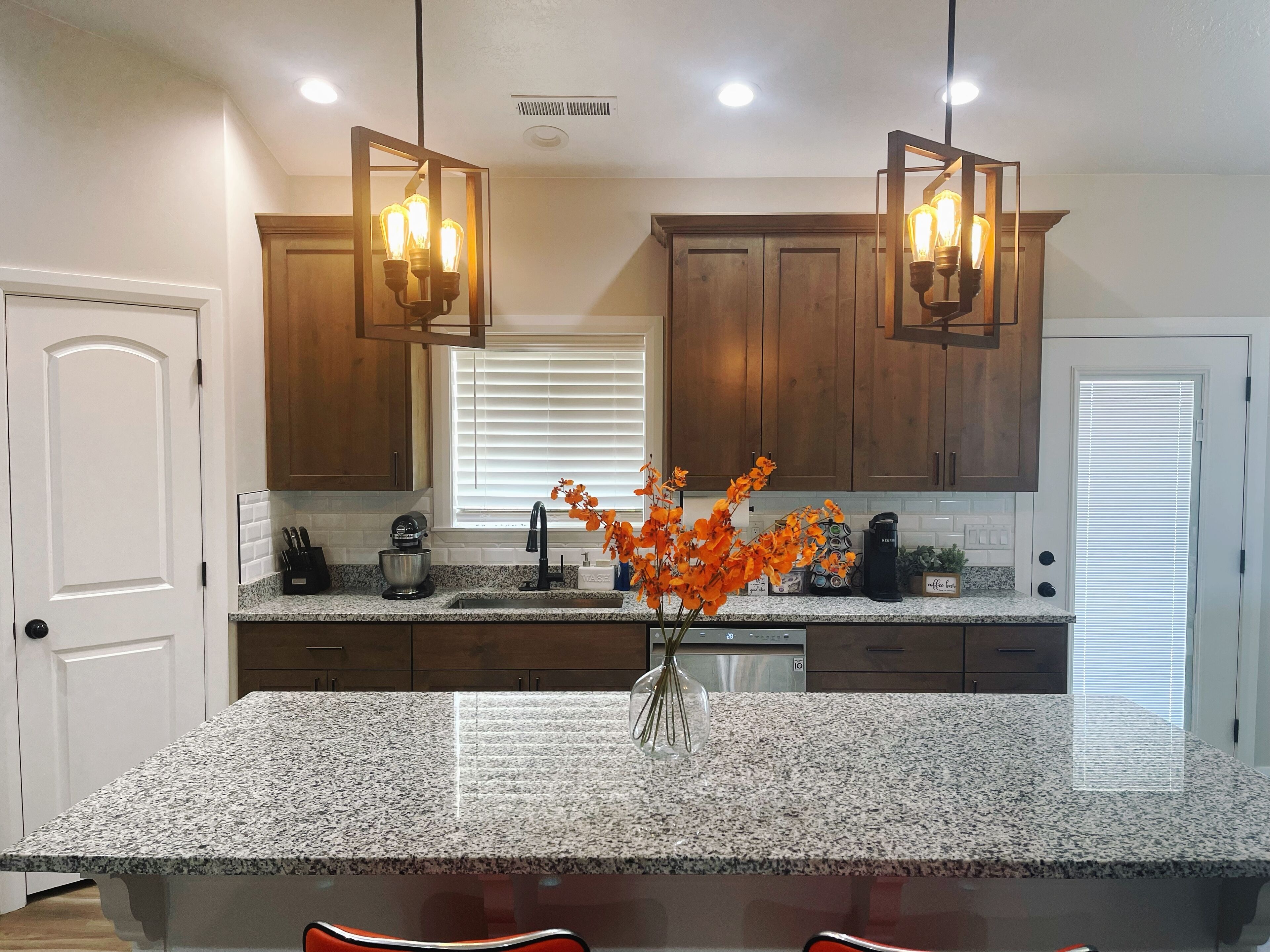 A kitchen with granite countertops, wooden cabinets, a built-in oven, and pendant lighting.