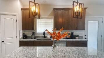 A kitchen with granite countertops, wooden cabinets, a built-in oven, and pendant lighting.