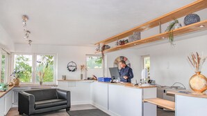 Eine moderne Küche mit integrierter Kücheninsel, einem schwarzen Ledersofa und einer Holzbalkendecke mit Pendelleuchten.