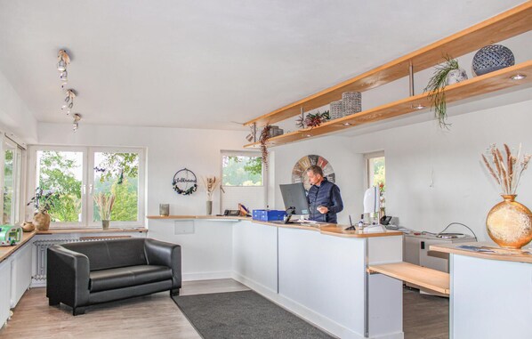 Una cocina moderna con una isla integrada, un sofá de cuero negro y un techo de madera con luces colgantes.