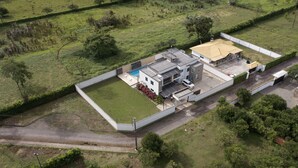 Vista aérea de um edifício moderno com piscina, área externa coberta e estacionamento.