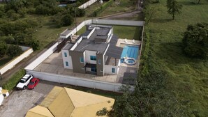 Vista aérea de um edifício moderno com piscina, área de estacionamento coberta e um pequeno jardim.