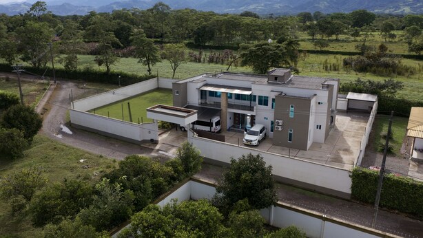 Um edifício moderno com telhado plano, amplas janelas e área de estacionamento coberta.