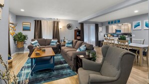 A modern living room with a sofa set, a coffee table, and a dining area with a table and chairs. - Luxury 3-bedroom Tri-Level w/ Game Room (Hoquiam)