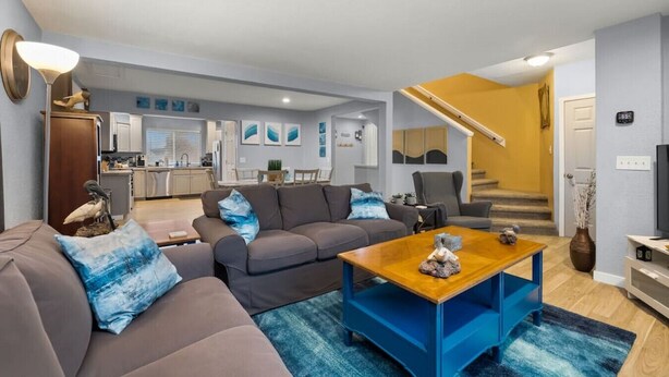 A modern living room with a sofa, coffee table, and a staircase leading to a second floor. - Luxury 3-bedroom Tri-Level w/ Game Room (Hoquiam)