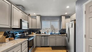 A modern kitchen with light-colored cabinets, stainless steel appliances, and a wooden countertop. - Luxury 3-bedroom Tri-Level w/ Game Room (Hoquiam)
