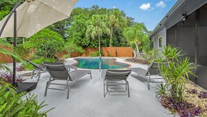 A backyard with a swimming pool, lounge chairs, and a pergola. - Your Private Tropical Paradise with Heated Pool! (Sarasota)