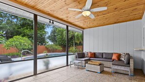 A modern outdoor living area with a wooden ceiling, large glass windows, and a pool. - Your Private Tropical Paradise with Heated Pool! (Sarasota)