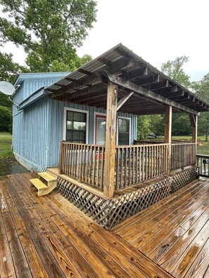 A wooden deck with a covered porch and a small building with a satellite dish.