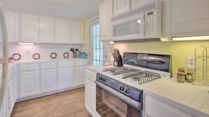 A kitchen with white cabinets, a stainless steel stove, and a microwave. - Lovely Pottsboro Home w/ Patio & Fire Pits! (Pottsboro)