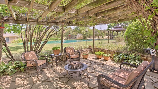 An outdoor patio with wicker furniture, a fire pit, and potted plants. - Lovely Pottsboro Home w/ Patio & Fire Pits! (Pottsboro)