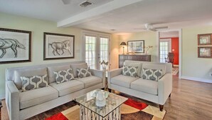 A living room with two grey sofas, a glass coffee table, and framed artwork on the walls. - Lovely Pottsboro Home w/ Patio & Fire Pits! (Pottsboro)