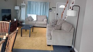 A living room with two sofas, a coffee table, a lamp, and a staircase.