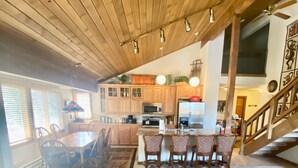 A cozy living room with a patterned sofa, a dining area with wooden chairs, and a kitchen with wooden cabinets and appliances. - Mountain Back (Mammoth Lakes)