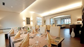 Un comedor con mesas dispuestas para una comida, una zona de bar y vistas del espacio del comedor.