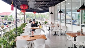 An outdoor dining area with tables and chairs, red lanterns, and a view of the street. - Cordela Inn Millennium Medan (Dwi Kora)