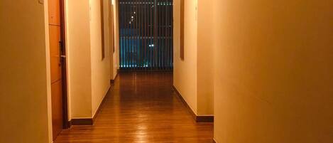 A narrow hallway with wooden flooring and beige walls.