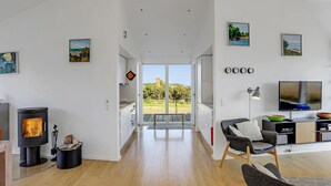 Un soggiorno moderno con camino, televisione e zona pranzo vista all'esterno.