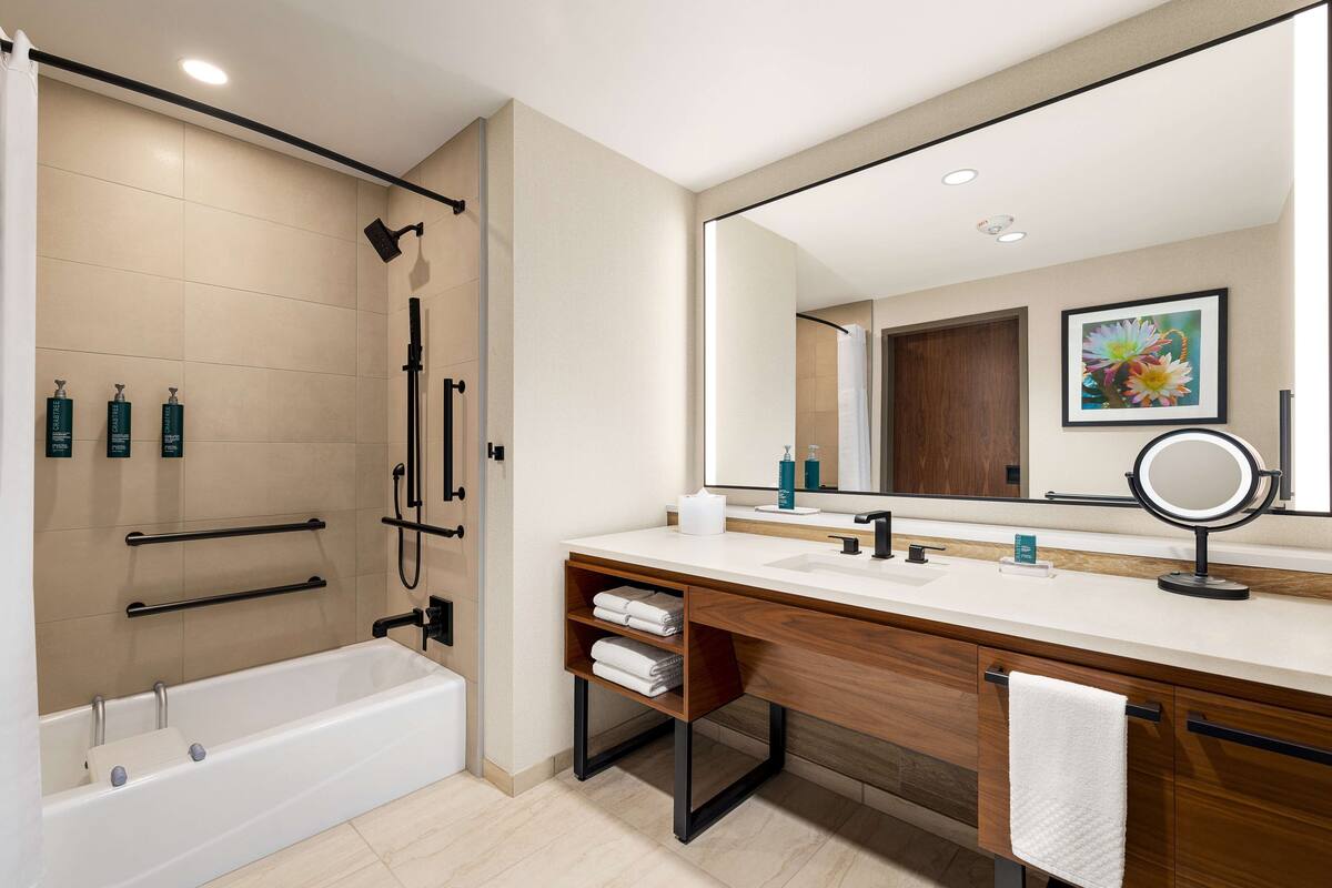 Ein modernes Badezimmer mit einer Badewanne, einem großen Spiegel und einem Waschtisch.