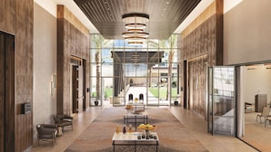 A spacious lobby with a central table set for a small gathering, flanked by seating and a modern ceiling design.