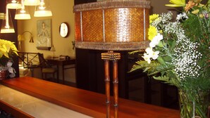 A room with a wooden table, a decorative lamp, hanging lights, and a floral arrangement. - Hotel Arcea Palacio de las Nieves (Oviedo)