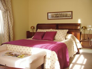 A neatly made bed with a pink blanket and pillows, a bedside table with a lamp, and a framed picture on the wall. - Hotel Arcea Palacio de las Nieves (Oviedo)