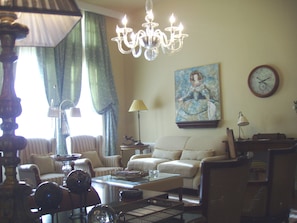 Un salon avec un lustre, un tableau, une horloge et un canapé.