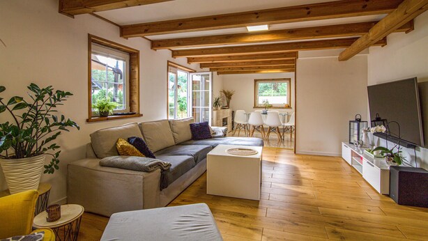 A spacious living room with wooden beams, a grey sofa, a coffee table, and a TV. - Beautiful home in Czarny Mlyn with WiFi (Czarny Mlyn)