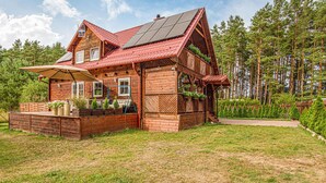 A wooden cabin with a red roof, solar panels, and a garden area with potted plants. - Beautiful home in Czarny Mlyn with WiFi (Czarny Mlyn)