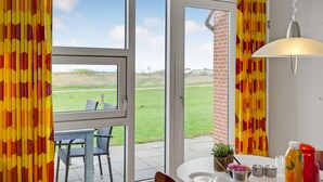 Ein Zimmer mit großen Fenstern, einem Tisch mit einer Topfpflanze und einer Pendelleuchte.
