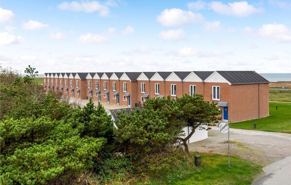 Une rangée d’immeubles en briques, tous de conception uniforme, avec de nombreuses fenêtres et un toit plat.