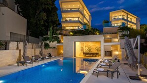 Un hotel moderno con piscina, asientos exteriores y una fachada bien iluminada.
