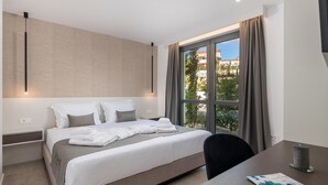Una habitación de hotel moderna con una cama grande, un escritorio y un ventanal con cortinas.