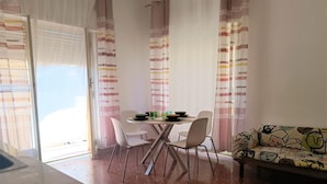 Ein Essbereich mit Tisch, Stühlen, einer Couch und Vorhängen.