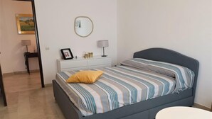 Ein Schlafzimmer mit einem Bett, einem Nachttisch, einer Lampe und einem kleinen runden Tisch.