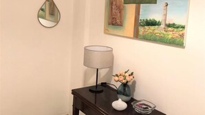Ein Zimmer mit einem dunklen Holztisch, einer Lampe, einer Vase mit Blumen und einem Wandbild.