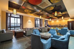 Um hall de hotel com áreas de estar, um bar e vista para a cidade.