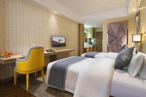 A hotel room with a bed, a desk, a chair, a television, and a mirror.