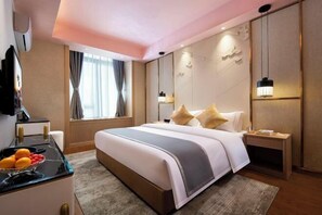 A hotel room with a large bed, bedside tables, a TV, and a fruit bowl.