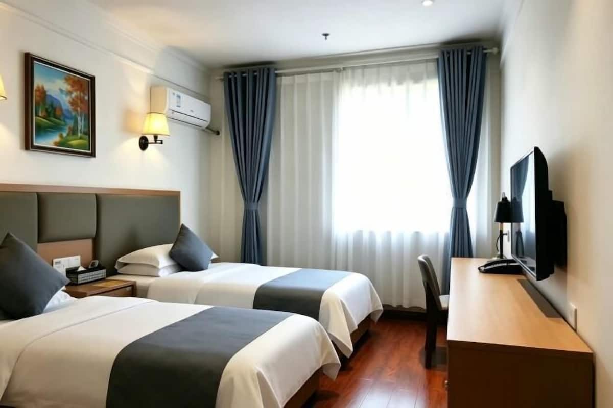 A hotel room with two beds, a desk, a chair, a television, and a painting on the wall.