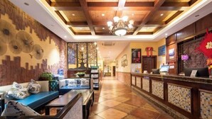 Un hall d’hôtel comprenant un comptoir d’accueil, un espace salon et des panneaux muraux décoratifs.