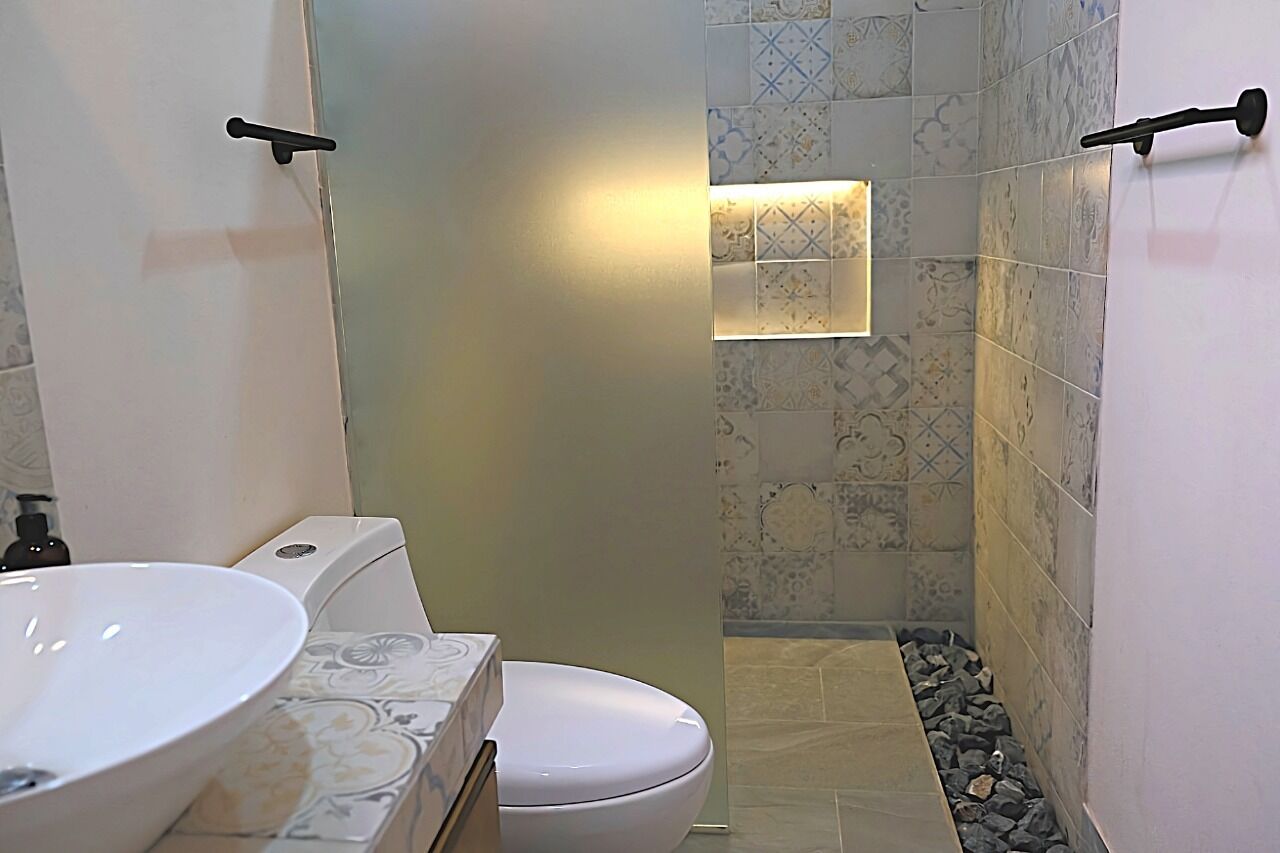 Une salle de bain avec un lavabo, des toilettes et une douche, le tout de couleur blanche.