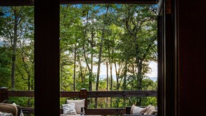 An outdoor seating area with a view of a forest and a body of water. - Cozy Bear Lodge Log Cabin, Big Green Egg, Outdoor Grill Station, Hot Tub grotto (Morganton)