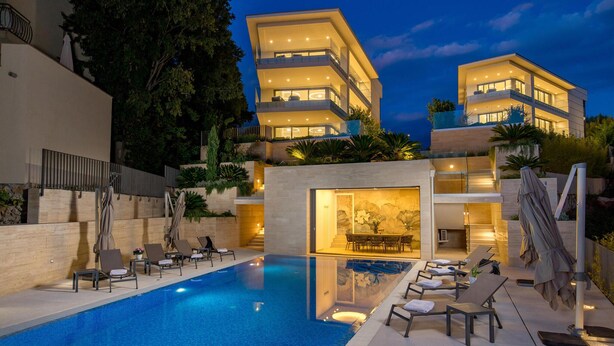 Un hôtel moderne doté d’une piscine, de nombreux balcons et d’un intérieur bien éclairé.