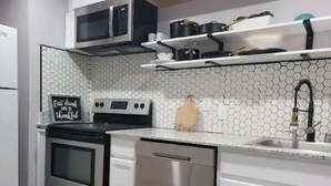 Une cuisine moderne équipée d’appareils électroménagers en acier inoxydable, d’un four à micro-ondes et d’une pancarte sur laquelle on peut lire : « Mangez, buvez et soyez reconnaissant. »