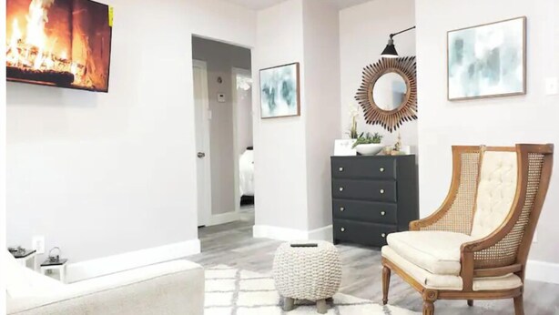Un salon moderne avec une cheminée, un canapé, un fauteuil et un petit pouf.
