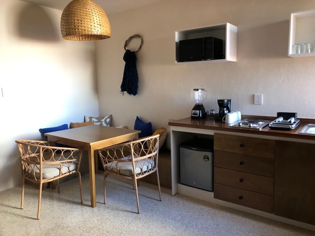 Une cuisine compacte avec une table et des chaises en bois, un four à micro-ondes encastré, un mixeur et une machine à café.