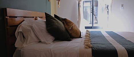 A neatly made bed with a wooden headboard, a dark striped bedspread, and multiple pillows.