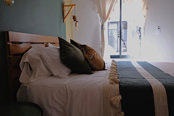 A neatly made bed with a wooden headboard, a dark striped bedspread, and multiple pillows.