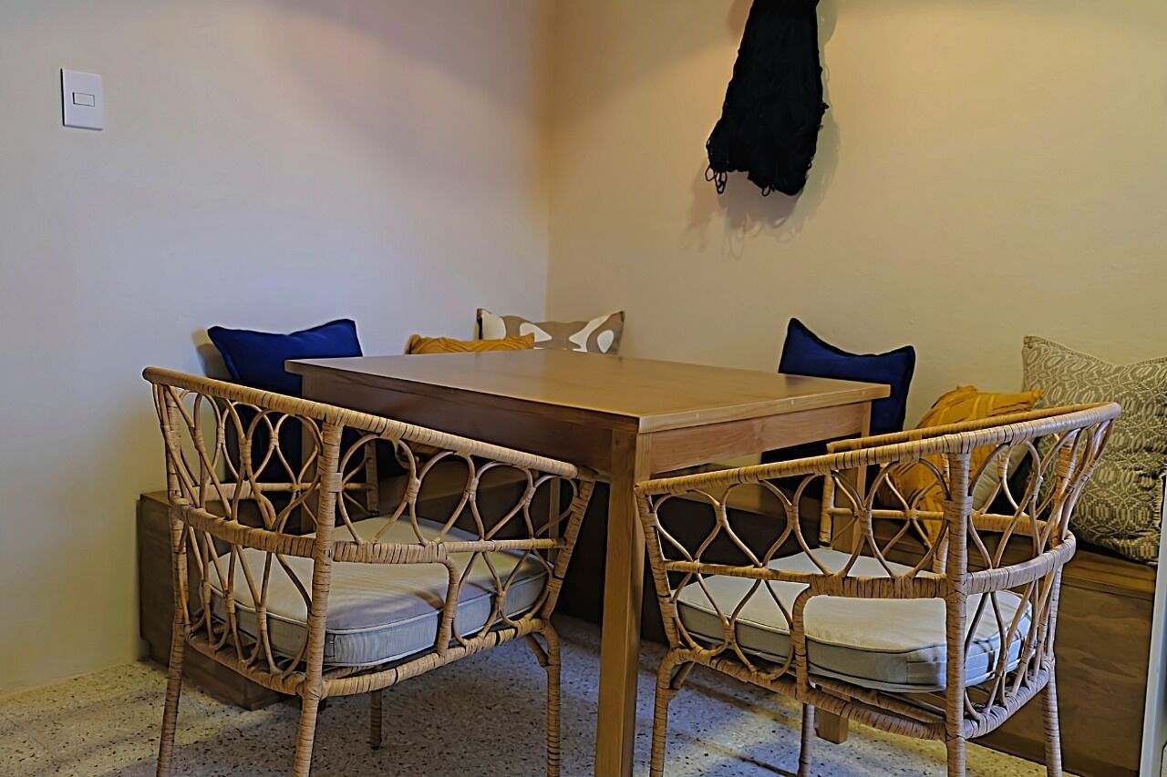 A dining area with a wooden table and wicker chairs.